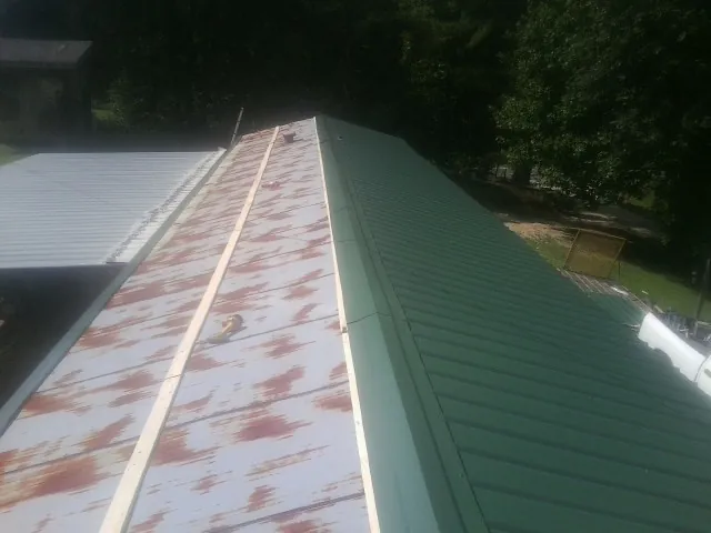 Old rusted panels beside newly installed green metal roofing — Wind Damage Roof Repair by Roofing Brothers in Red Boiling Springs