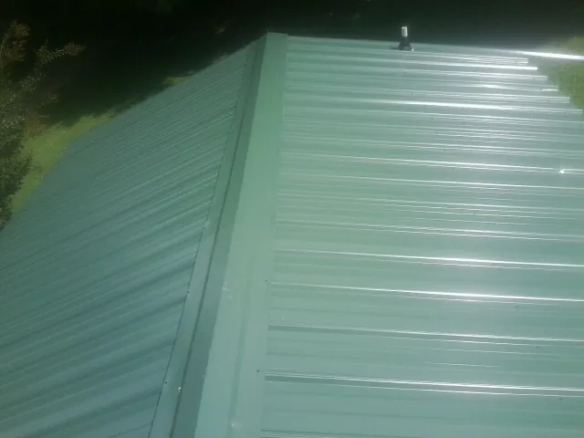New green metal panels meeting at the ridge of a roof — Flat Roof Repair work by our crew in Red Boiling Springs