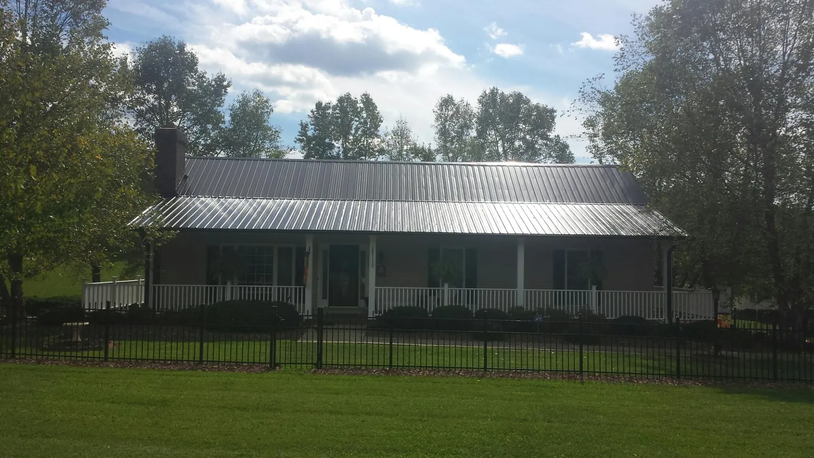 Gray metal roof on a brick ranch with a full width front porch — Gutter Guard Installation work by our crew in Red Boiling Springs