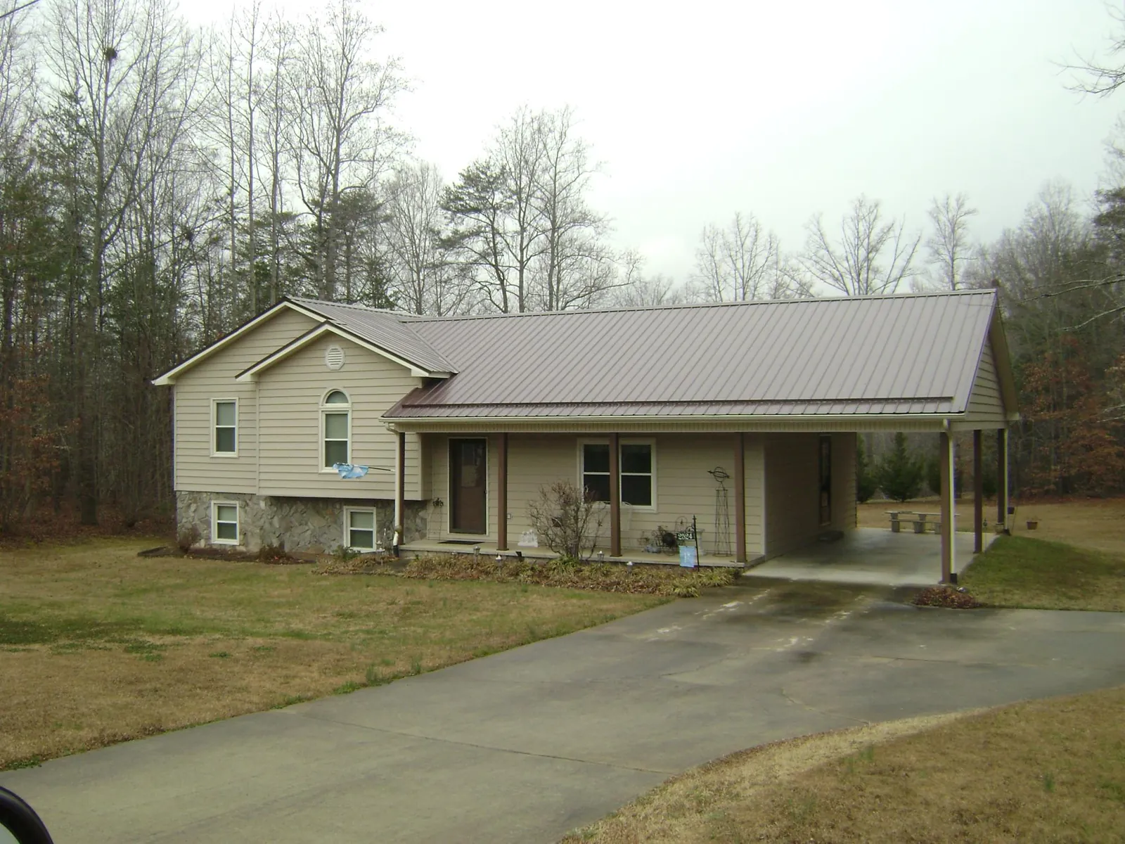 Brown metal roof on a tan split level home with an attached carport in Red Boiling Springs