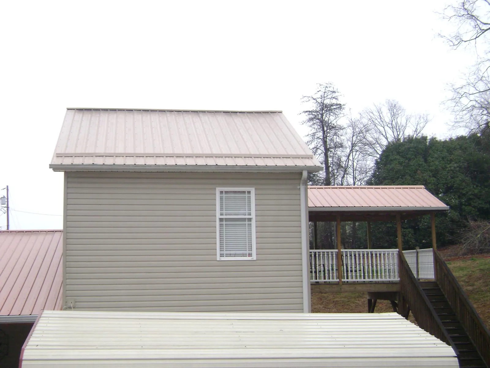 Tan metal roofs on a two story addition and attached porch, from a Roof Replacement job in Red Boiling Springs