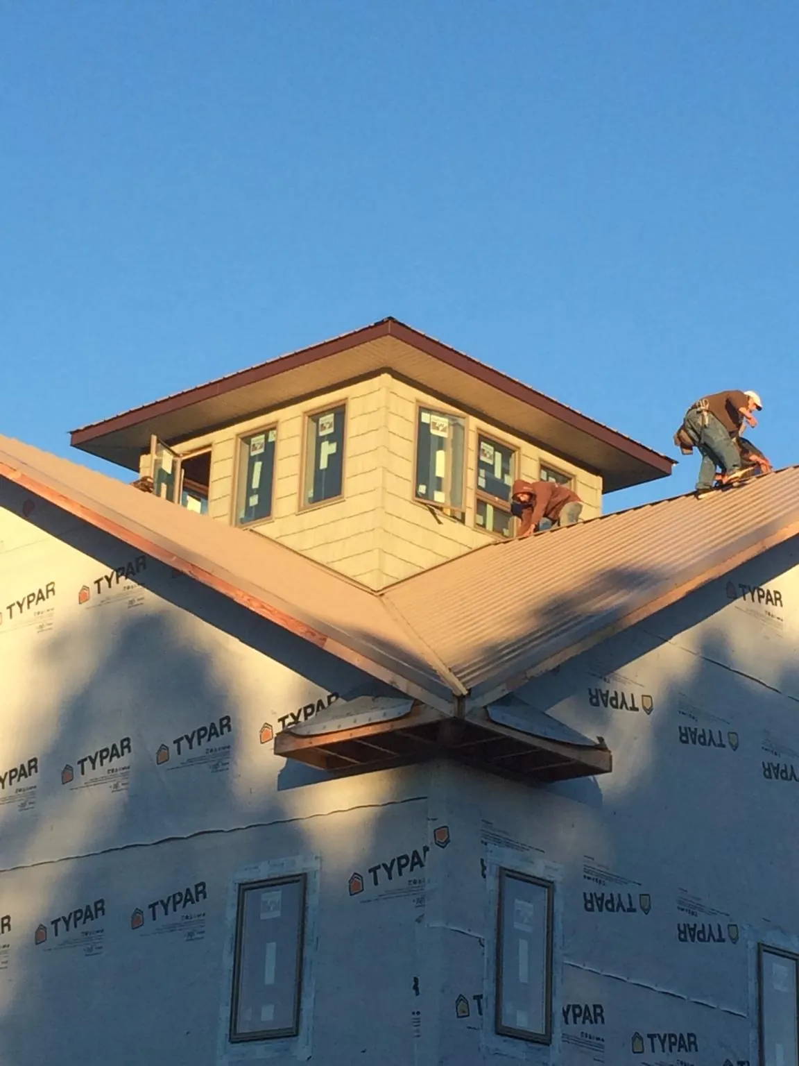 Roofers working around a rooftop cupola on a new metal roof at sunset — Roof Waterproofing in Red Boiling Springs by Roofing Brothers